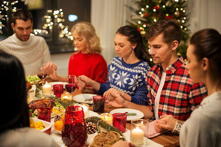 节日庆祝朋友牵手祈祷,同时家里吃诞晚餐朋友们回家吃诞晚餐祈祷图片