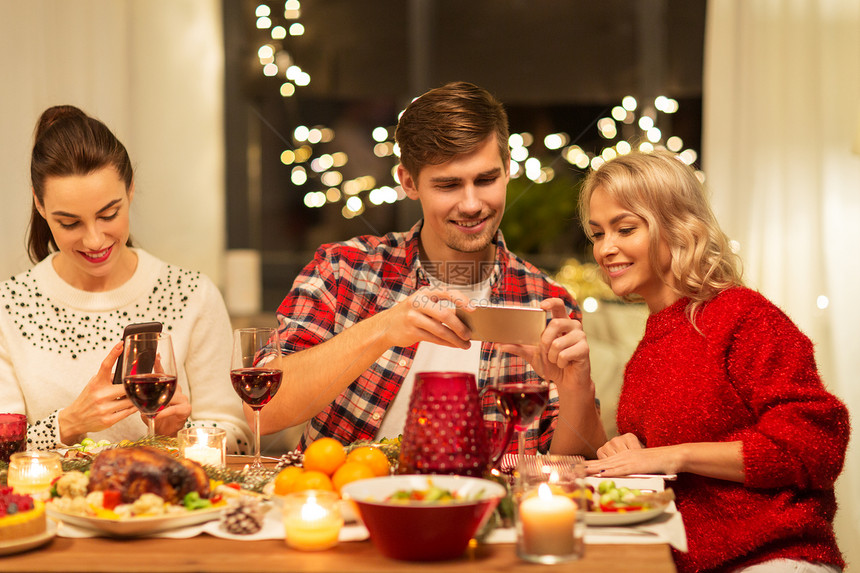 节日庆祝快乐的朋友家里吃诞晚餐,用智能手机拍摄食物快乐的朋友家吃诞晚餐图片