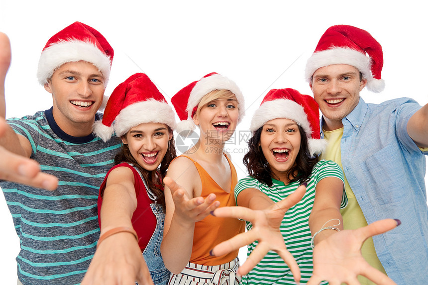 诞节,假日友谊的群快乐的微笑的朋友戴着诞老人的帽子,白色的背景下玩得很开心白色背景的诞老人帽子里的快乐朋友图片