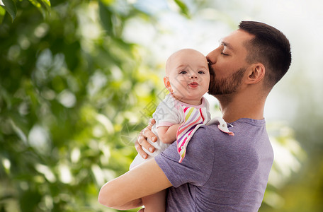 家庭,父母人的快乐的父亲亲吻小宝贝女儿绿色的自然背景父亲亲吻小女儿图片