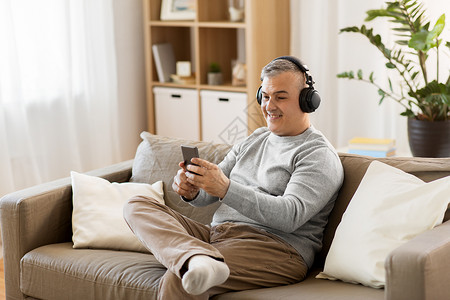 技术,人生活方式的快乐的人与智能手机耳机听音乐家家里智能手机耳机的男人图片