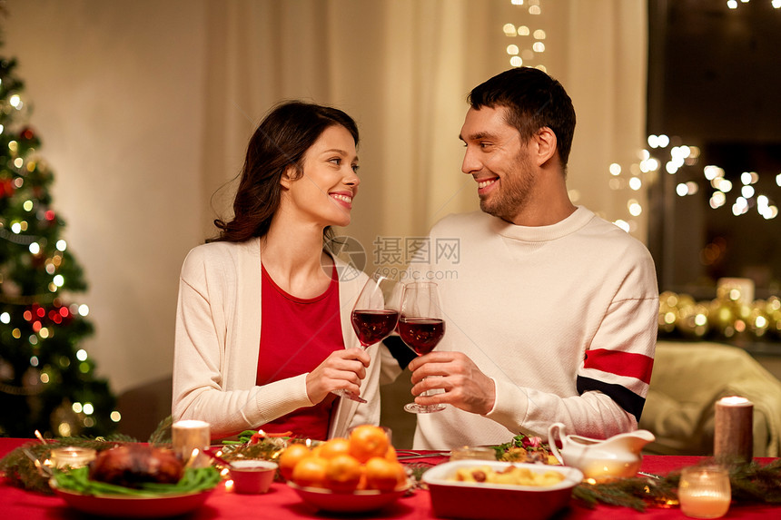 节日,家庭庆祝快乐的夫妇家里吃诞晚餐,喝红酒碰杯快乐的夫妇诞晚餐上喝红酒图片