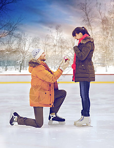 求婚,浪漫爱情幸福的夫妇与订婚戒指户外溜冰场溜冰场上戴戒指的男人图片