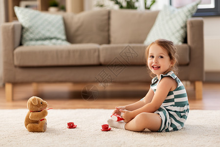 玩玩具熊的女孩童人的快乐的三岁女婴玩茶玩具陶器泰迪熊家里小女孩家玩玩具茶具背景