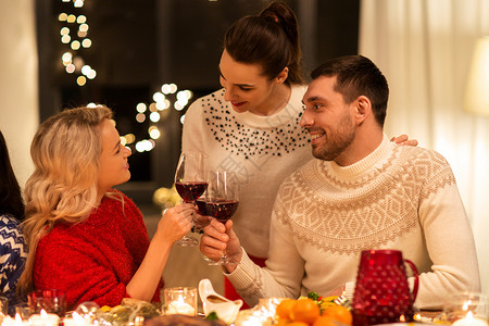 节日庆祝快乐的朋友家里吃诞晚餐,喝红酒碰杯快乐的朋友诞节聚会上喝红酒图片