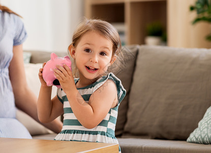 储蓄金融快乐的小女孩家里储蓄罐带着储蓄罐的快乐小女孩图片