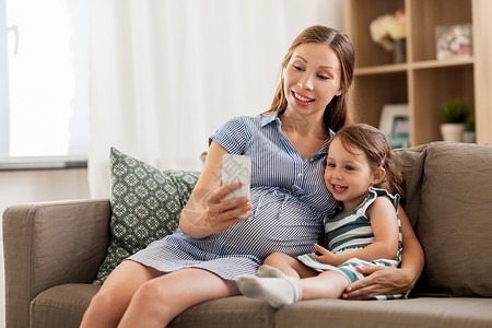怀孕,人家庭的快乐的怀孕母亲小女儿家里智能手机怀孕的母女智能手机图片