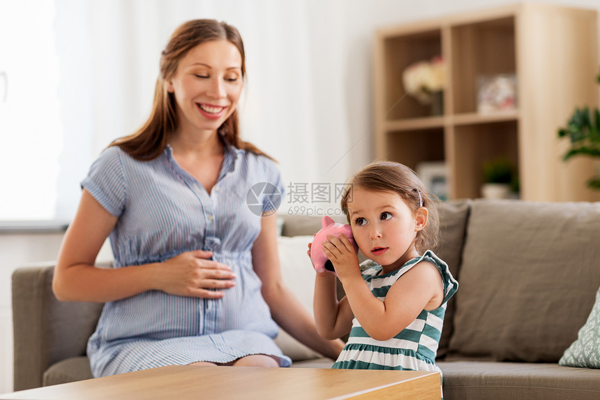 怀孕,财务家庭快乐的怀孕母亲小女儿家里储蓄罐怀孕的母亲女儿带着储蓄罐图片