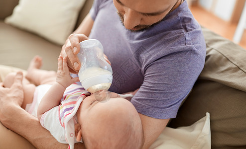 家庭,父母人的亲密的父亲喂养小女儿与婴儿配方奶粉瓶家里父亲瓶子喂养婴儿图片