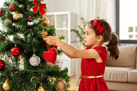 寒假,慈善人们的快乐的小女孩家里用红心玩具装饰诞树小女孩家装饰诞树图片