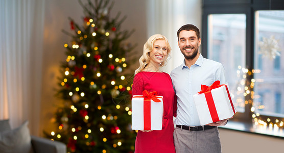 人假日幸福的夫妇与礼品盒家庭房间诞树背景家里诞礼物的幸福夫妇图片