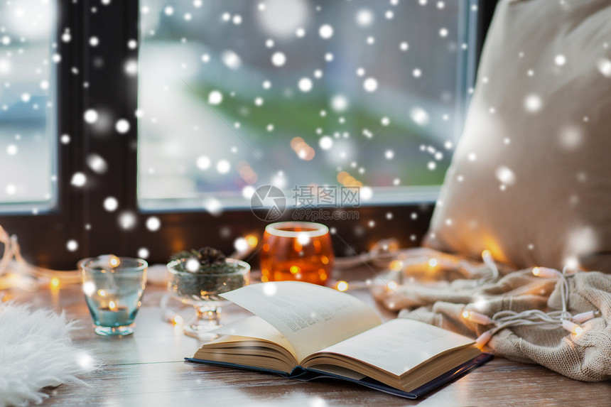 潮湿,诞节舒适的家庭书,花环灯蜡烛窗台上的雪窗台上的书花环灯蜡烛图片