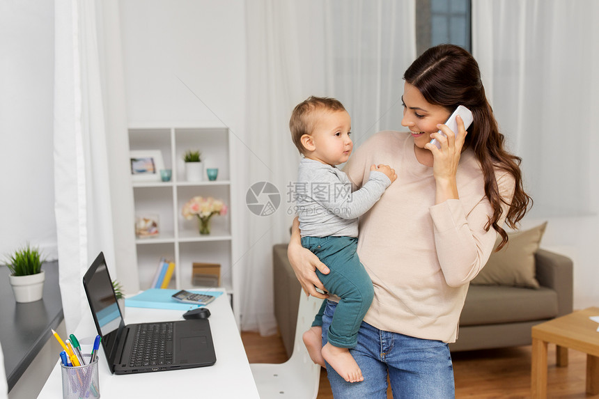 母亲,多任务,家庭技术快乐的母亲与婴儿打电话家里的智能手机母亲带着婴儿家里打电话给智能手机图片