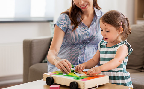 童人们的快乐的怀孕母亲小女儿家里玩玩具积木怀孕的母亲女儿带着玩具块图片