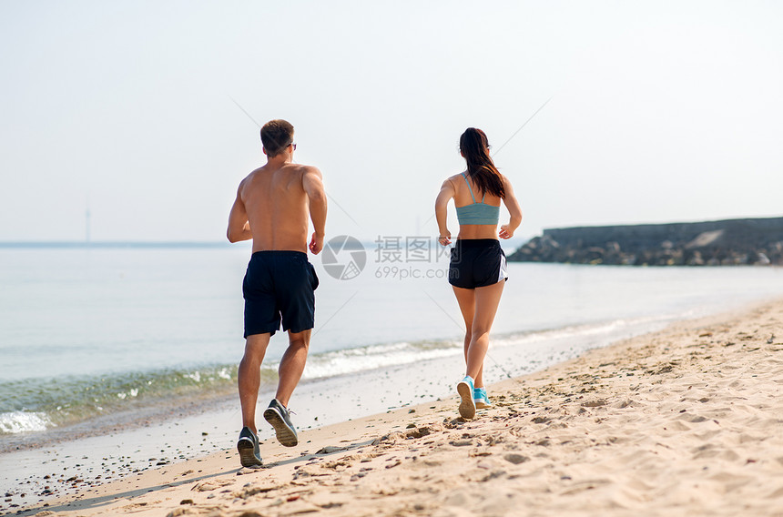 健身,运动生活方式的快乐的夫妇沿着夏天的海滩跑步穿着运动服的夫妇海滩上跑步图片