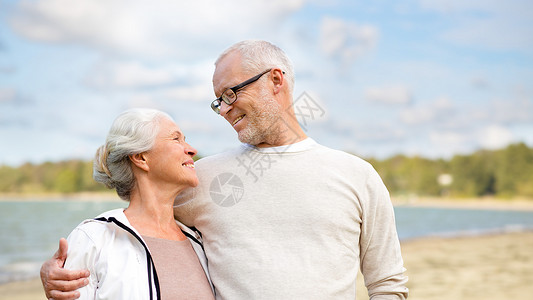 老,退休人们的快乐的老夫妇拥抱海滩背景快乐的老夫妇拥抱海滩背景图片