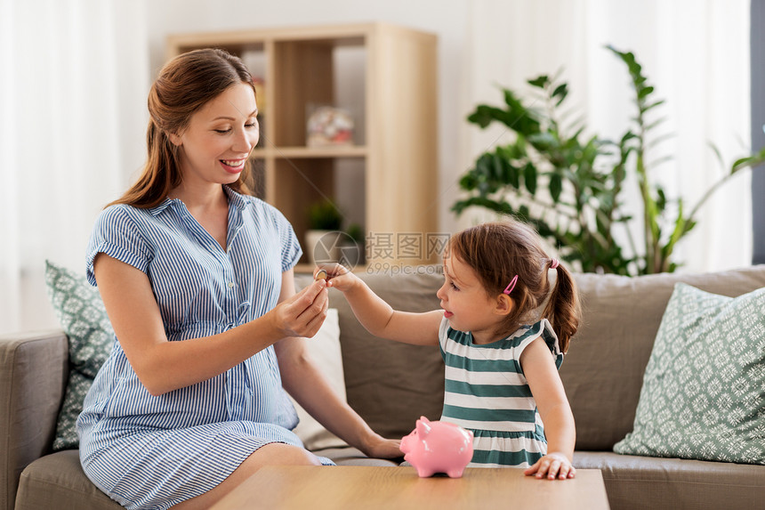 怀孕财务家庭观念快乐的怀孕母亲小女儿家里把欧元硬币放进储蓄罐里怀孕的母亲女儿带着储蓄罐图片
