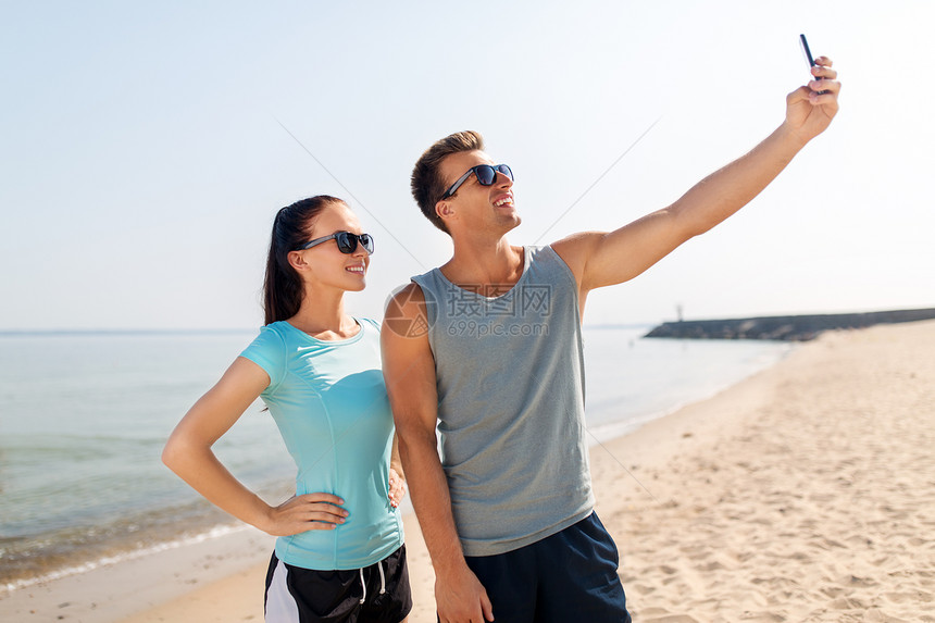 健身,运动生活方式的快乐的夫妇穿着运动服,海滩上用智能手机自拍夫妇海滩上用智能手机自拍图片