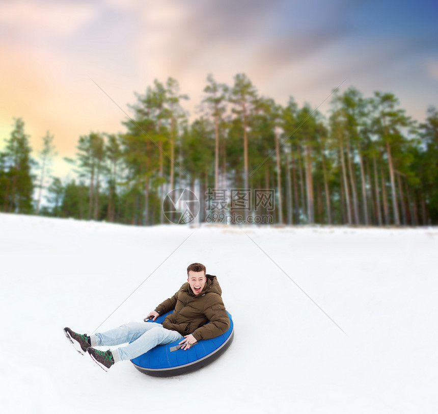 冬季,休闲娱乐活动的快乐的轻人滑下山雪管上的自然背景快乐的轻人雪管上滑下山图片