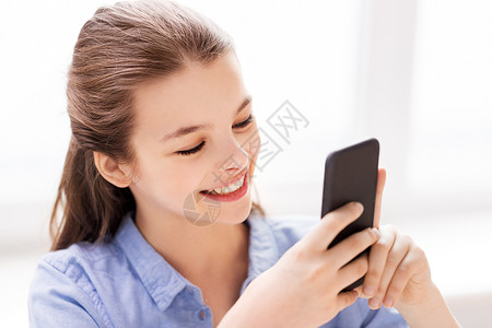 儿童,技术沟通微笑女孩家里智能手机短信微笑的女孩家里的智能手机上发短信图片