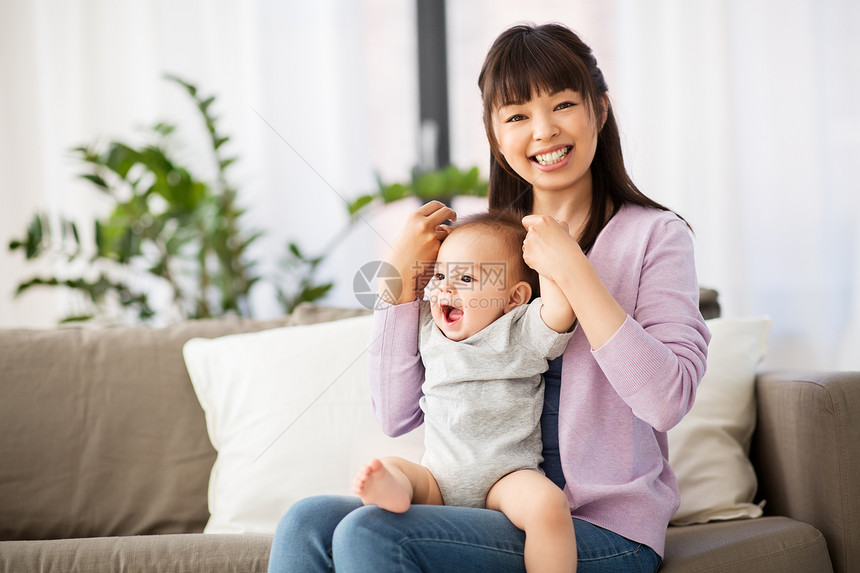 家庭母亲的快乐微笑的轻亚洲母亲小婴儿家里快乐的轻亚洲母亲小婴儿家里图片