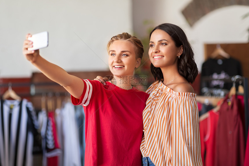 销售,购物技术快乐的女朋友老式服装店用智能手机自拍女朋友服装店自拍图片