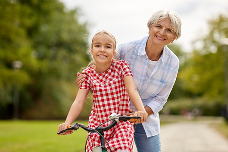 家庭休闲人的快乐的祖母夏季公园教孙女骑自行车祖母孙女骑自行车图片