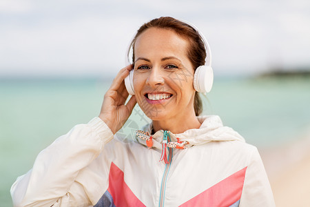 技术人的微笑的女人带着耳机海滩上听音乐带着耳机海滩上听音乐的女人图片