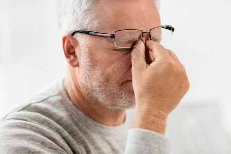 压力,老人人的接近老人戴眼镜头痛按摩鼻梁戴眼镜的老人按摩鼻梁背景