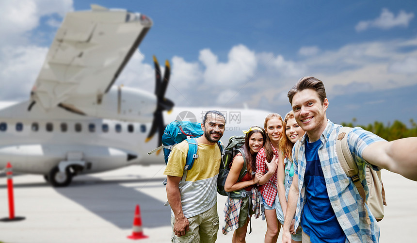 旅行,旅游人的群微笑的朋友游客带着背包机场背景下的飞机上自拍朋友们机场的飞机上自拍图片