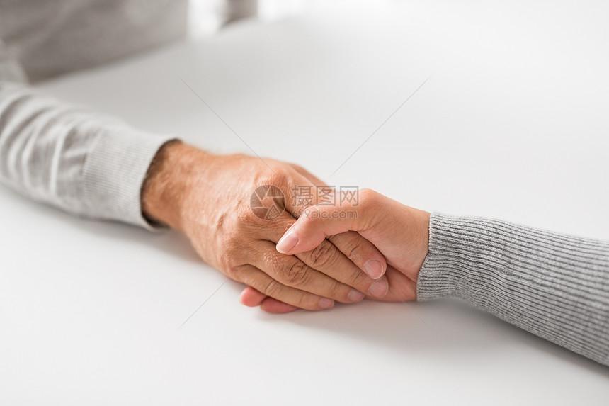 老家庭关心支持的密切轻妇女牵着老男子的手紧紧地抓住轻女子握着高级男子的手图片