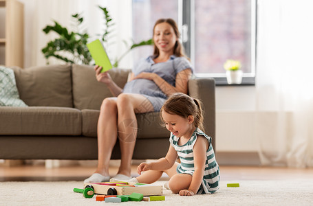 童人的快乐的三岁女婴玩玩具积木怀孕的母亲家看书快乐的女婴家里玩玩具积木背景图片