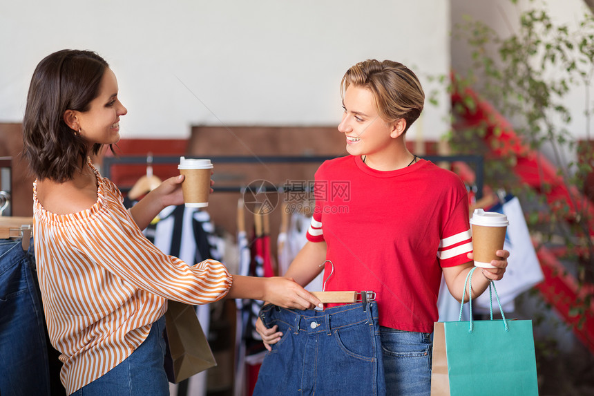 销售,购物,时尚人们的快乐的轻女带着外卖咖啡杯老式服装店选择衣服老式服装店喝咖啡的快乐女人图片