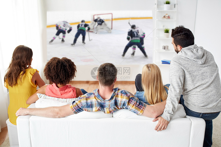 运动,人娱乐活动的快乐的朋友看冰球比赛投影仪屏幕家里朋友们投影仪屏幕上看冰球图片