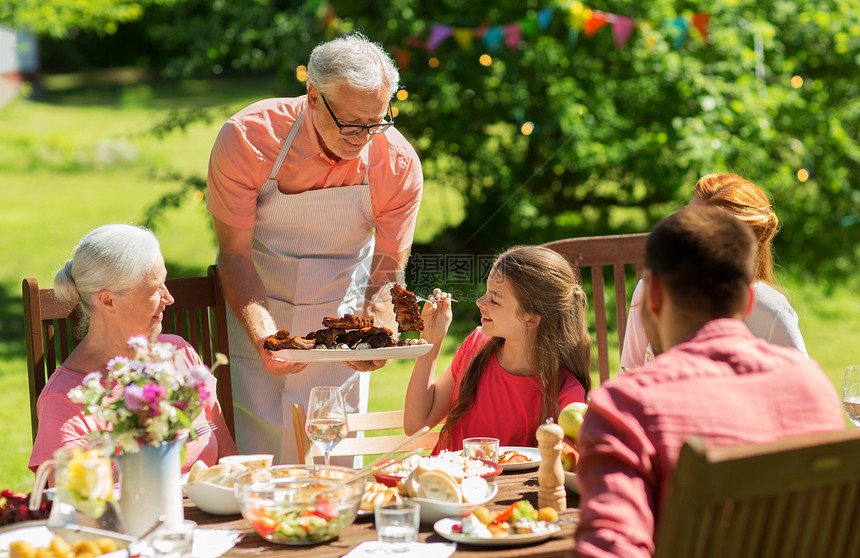 休闲,假日人们的快乐的家庭夏季花园举行节日晚餐烧烤聚会家人夏天的花园里吃晚饭烧烤图片
