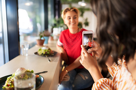 休闲技术人的女朋友餐馆咖啡馆用智能手机吃饭拍照咖啡馆吃午饭拍照的女人图片
