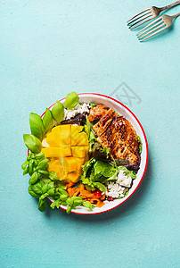 美味的沙拉与烤鸡胸切片芒果碗与餐具浅蓝色背景,顶部视图健康午餐图片