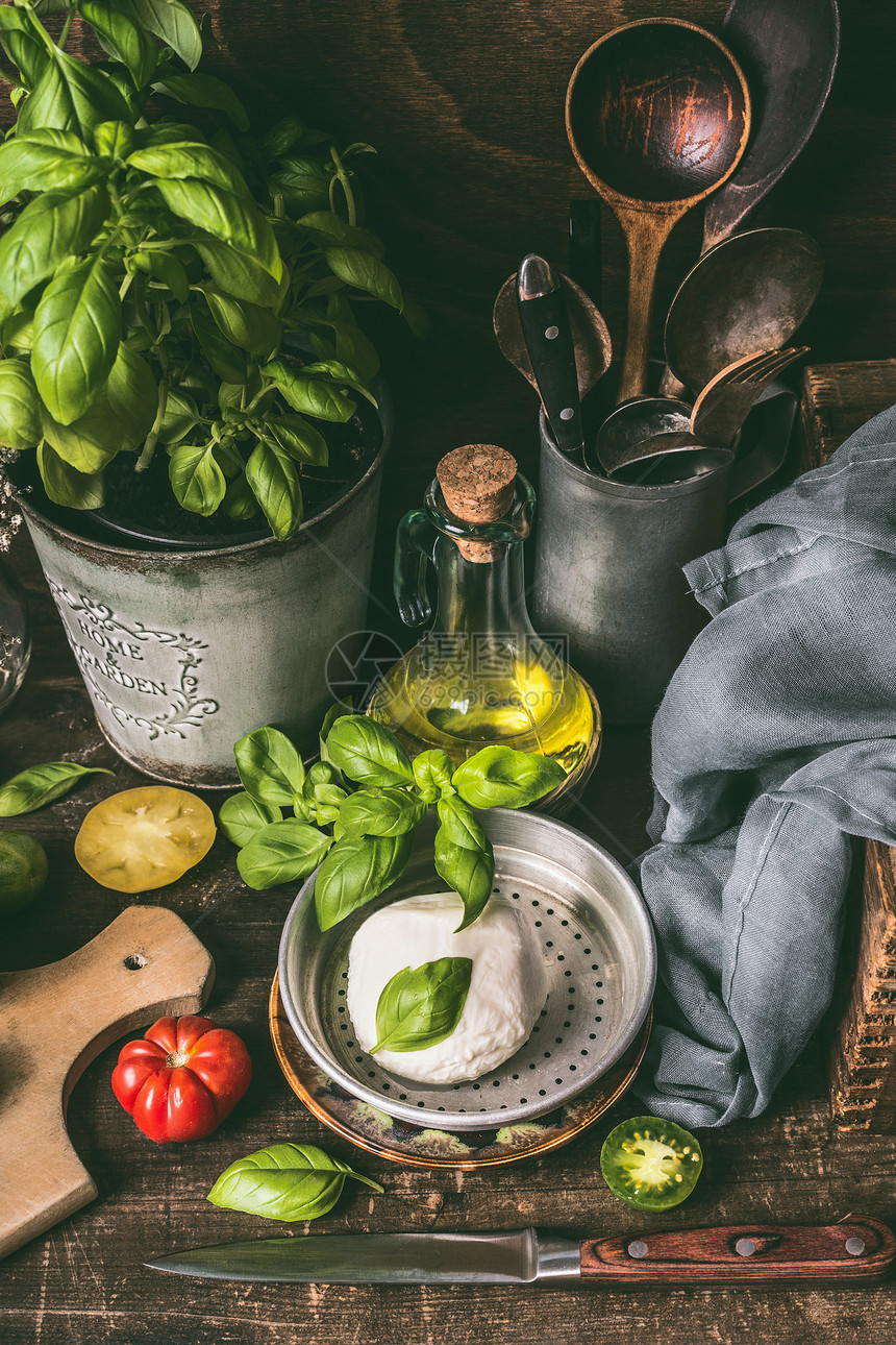 盘子上马苏里拉波拉塔,油罗勒乡村厨房桌子背景与配料烹饪工具乡村风格的食物背景,静物图片