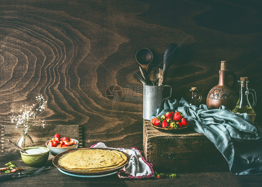 乡村生活与自制的薄饼黑暗的乡村木制厨房桌子上,草莓酸奶碗里图片