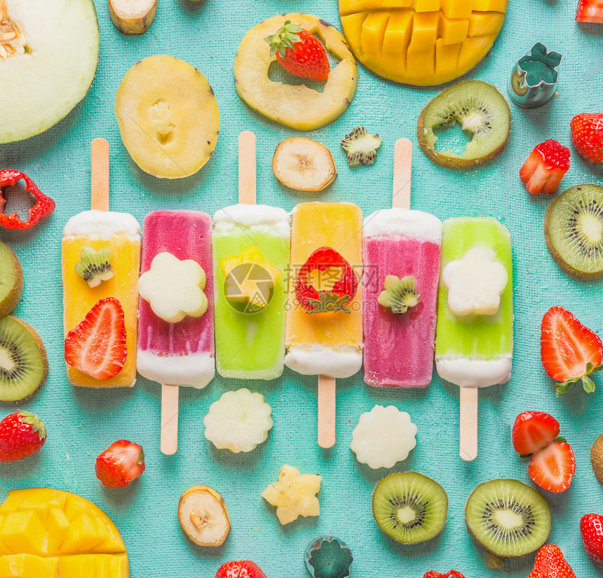 五颜六色的各种冰淇淋冰棒与新鲜切片水果浆果成分浅蓝色的背景,顶部的视图,平躺冷冻热带果汁带异国水果的自制冰淇淋图片