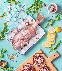 原始粉红色的多拉多鱼冰块上,烹饪原料浅蓝色厨房桌子背景,顶部视图,平躺海鲜图片