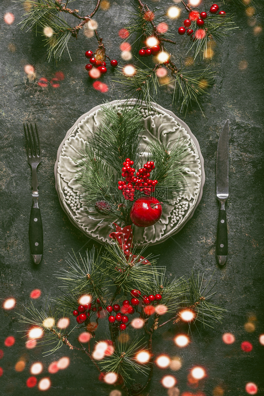 节日诞餐桌与Bokeh假日晚餐与盘子,餐具,冷杉树枝冬季浆果乡村背景,顶部的景观图片