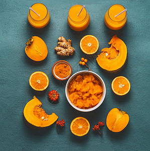 健康南瓜冰沙与橙色成分柿子,橙色水果,生姜姜黄粉蓝色背景,顶部视图,平躺冷季免疫增强饮料背景