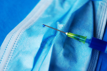 套管种带蓝色液体的注射器的详细,带蓝色背景的医用罩上的针头背景