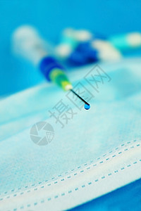 注射器针头用蓝色液体滴入针头的药丸带蓝色背景的医用罩上的注射器的详细背景