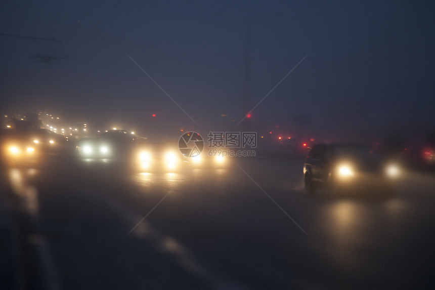 晚上,路灯的灯光下,汽车雾中行驶图片