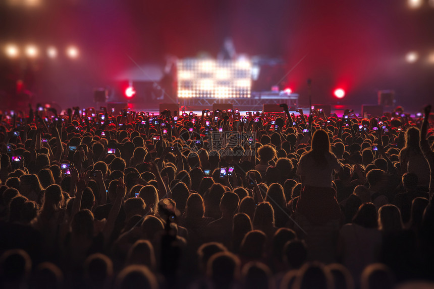 人们音乐会上用手机拍摄节目图片