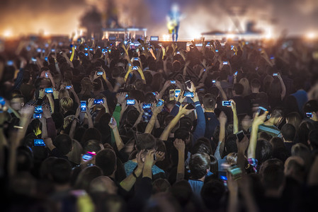 人们音乐会上用手机拍摄节目背景