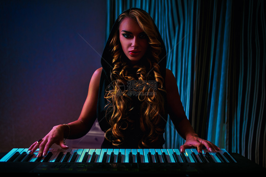 轻女子音乐家感时尚肖像黑暗的夜晚室内弹钢琴图片