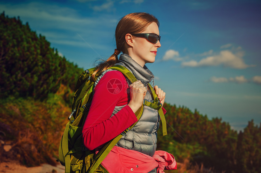 轻的女游客,绿色的背包太阳镜站山上的背景上图片